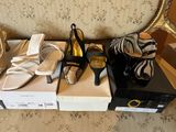 several pairs of women ' s shoes sitting on top of boxes in front of a chair