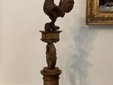 une statue de coq posée sur un socle dans une pièce