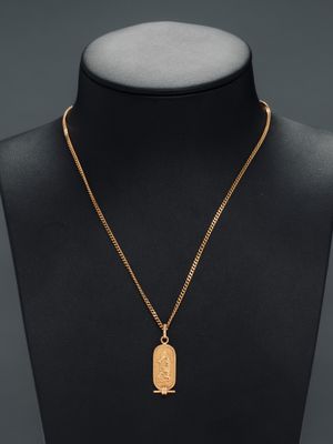 a gold plated necklace with a bird pendant on a mannequin neck