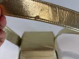someone is holding a gold belt that has a metal buckle on it