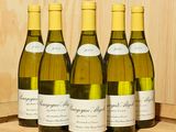 six bouteilles de vin blanc sont alignées sur un tonneau