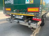 a green garbage truck parked on the side of the road
