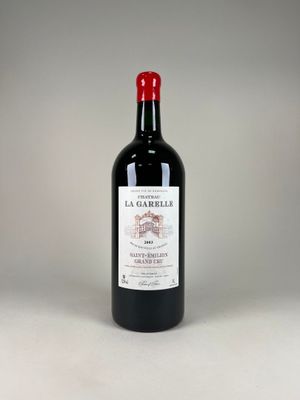 bottle of red wine with a red cap sitting on a white surface