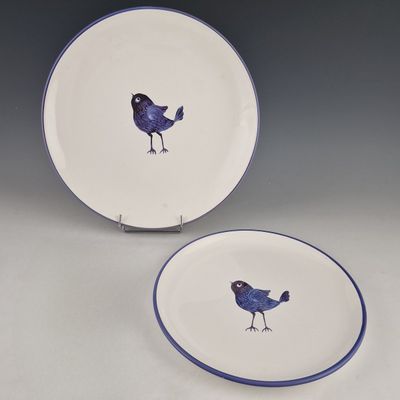 two plates with birds painted on them sitting on a table