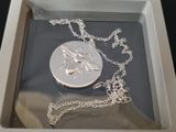 a silver necklace with a bee on it in a white box