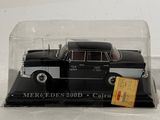 a black car in a glass case on a white surface