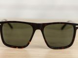sunglasses on a wooden table with a white wall in the background