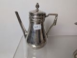 a silver tea pot sitting on a glass table