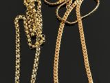 two gold chains with tags attached to them on a black surface