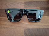 des lunettes de soleil posées sur une table en bois, avec une personne en train de prendre une photo
