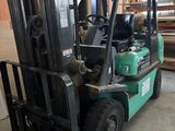 un chariot élévateur vert garé dans un entrepôt