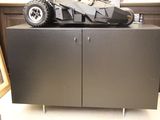 une Batmobile miniature posée sur une armoire dans une pièce