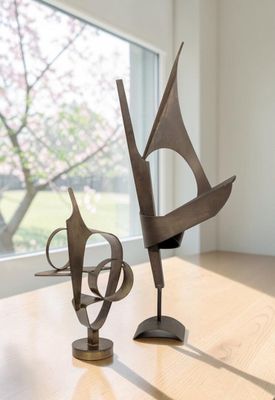 deux sculptures posées sur une table en bois devant une fenêtre