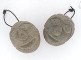 pair of carved stone ornaments on string on white background