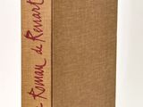 a brown book with red writing on it sitting on a white surface