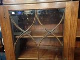 an antique oak bookcase with glass doors and a wooden shelf