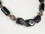 necklace made of black glass beads with silver accents on a white background