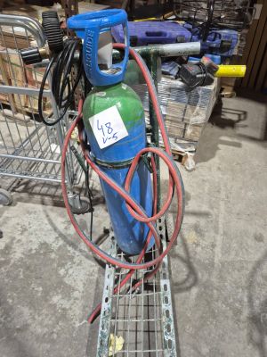 un réservoir de gaz bleu et vert posé sur un caddie