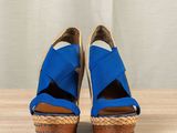 pair of blue espadrills on a wooden table with a curtain in the background