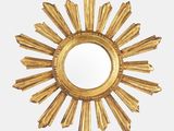 un miroir doré à rayons de soleil accroché à un mur blanc