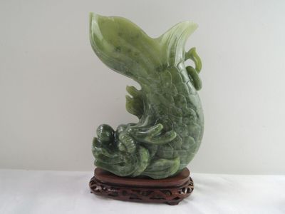 une statue verte représentant un poisson, posée sur un socle en bois