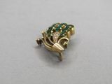 a green and gold frog brooch on a white surface
