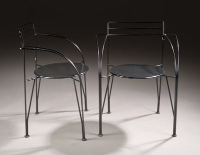 pair of black metal chairs sitting on top of a white floor