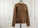 brown sweater on a mannequin stand in front of a white wall