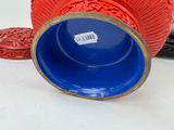 a red vase with a blue lid sitting on a table