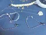 many different necklaces and bracelets laid out on a table