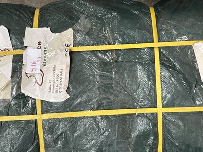 une bâche verte emballée dans du plastique et attachée à une corde jaune