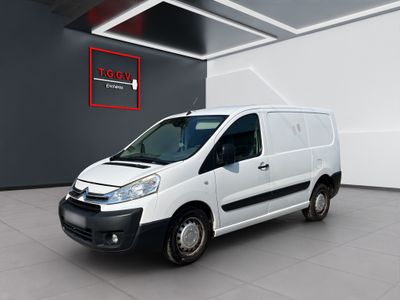 La camionnette blanche est garée dans une grande pièce où se trouve un panneau rouge.