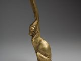 a gold figurine of a bird with a long tail