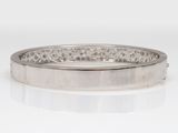 a close up of a silver bang bracelet on a white surface