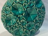 un vase vert posé sur une surface blanche, avec un fond blanc
