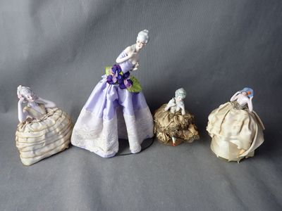 four porcelain figurines of women in dresses and hats on a gray background