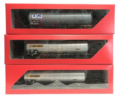 trois boîtes contenant des wagons de train miniature, posées sur une surface blanche
