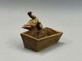 statue en bronze représentant un canard dans un bol posé sur une table
