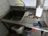 a dirty sink in a dirty kitchen with a bottle of milk