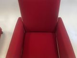 pair of red chairs with white piping on the arms and legs