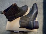 pair of men ' s brown leather boots sitting on top of a cardboard box