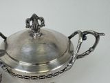 a silver bowl with a lid and a spoon on a table