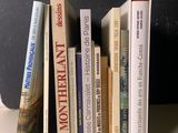 Plusieurs livres sont alignés sur une étagère devant un mur noir