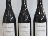 three bottles of wine are lined up on a white surface