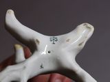someone is holding a white ceramic object with a cross on it