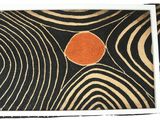 a black and orange rug with an orange dot on it