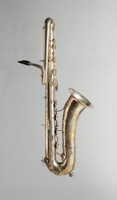 un vieux saxophone argenté posé sur un support en bois