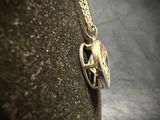 a silver necklace with a bird on it on a black surface