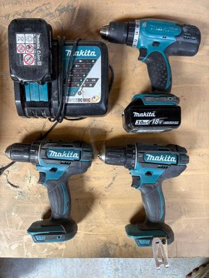 trois perceuses-visseuses sans fil Makita posées sur une table en bois