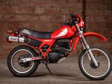 a red dirt bike parked in front of a brick wall